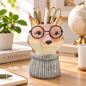 Orange and cream fox pen holder with round black glasses and a grey knit-look sweater on a desk