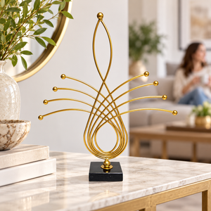 Gold abstract metal sculpture with black base displayed on a console table