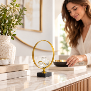 Decorative gold ring and crystal ball sculpture styled on a console table
